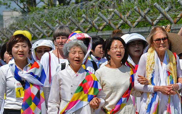Group of women wearing white outfits with multicolored sashes and scarves
