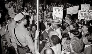 Black and white image of people at a protest with police officers looking on