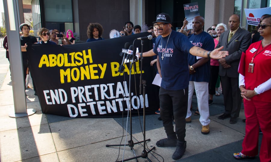 People marching with a banner that says Abolish Money bail End Pretrial Detention