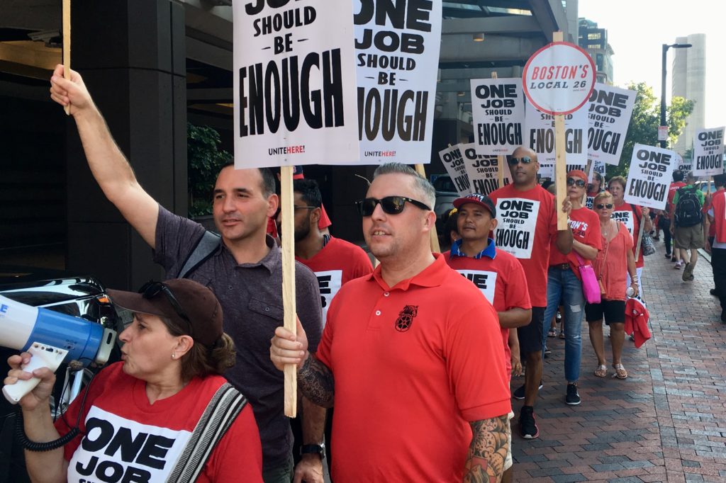 Men in a picket line with signs that say One job should be enough