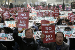 South Koreans at a rally holding up signs saying No Trump No War