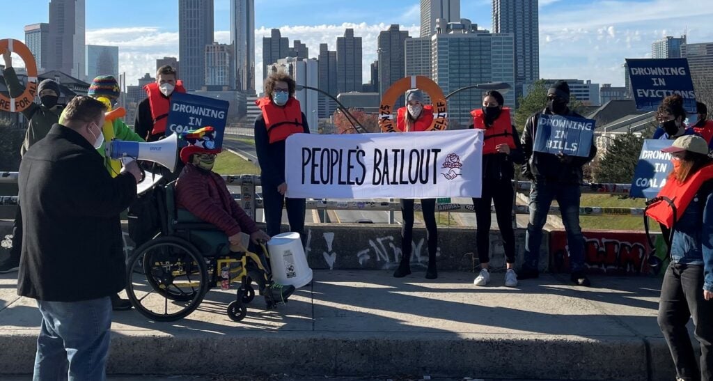 People at a protest with a banner that says "People's Bailout"