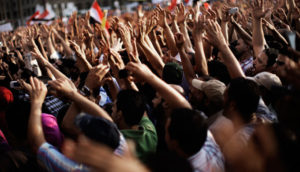 Photo of people at a protest with their hands held in the air