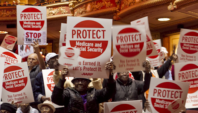 People holding up red and white signs that say Protect Social Security and Medicare