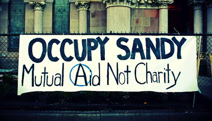 Banner hanging on a wall that says Occupy Sandy Mutual Aid not Charity