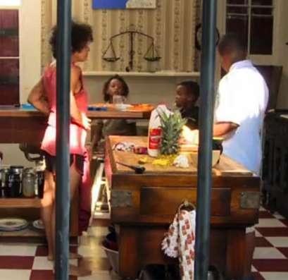 Photograph of 2 black people standing near a table being set for a meal