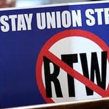 Photo of a sign that says stay union strong above a red circle with diagonal red line in which are the letters RTW