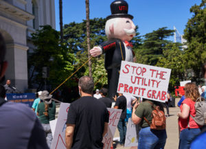 People at a protest, one sign that says Stop the Utility Profit Grab