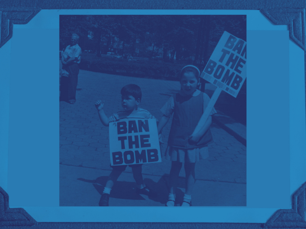 Alittle boy and a little girl, both holding signs that say "Ban the Bomb."