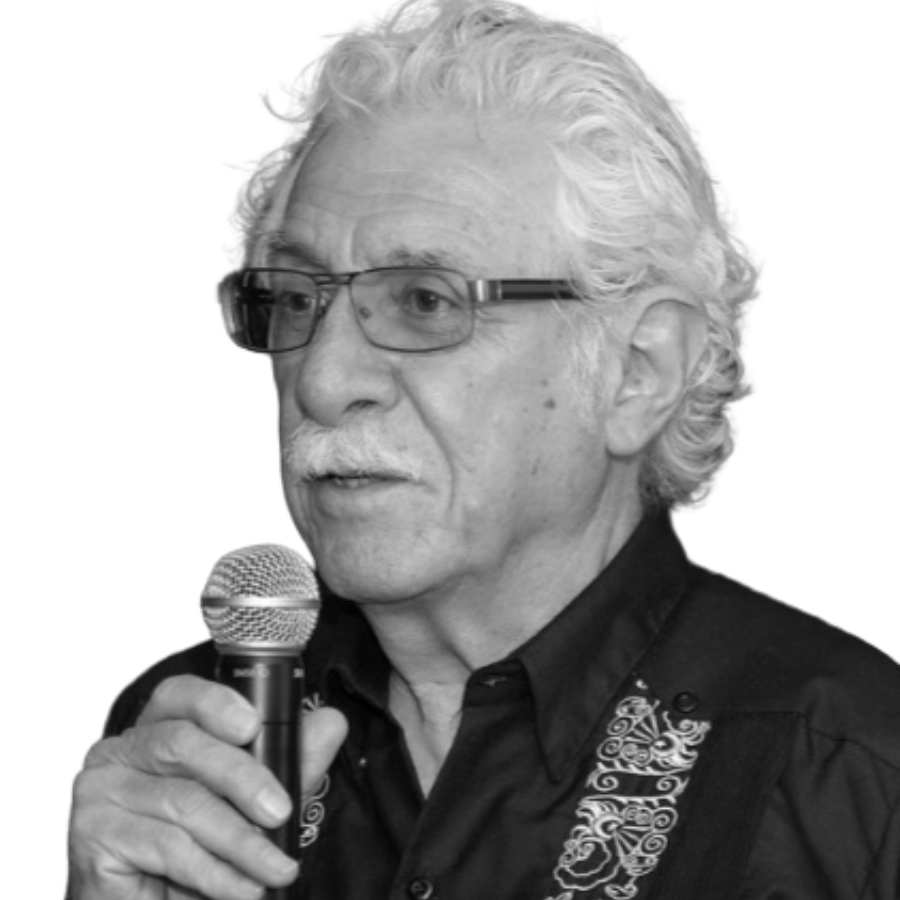 Black and white photo of Bill Gallegos holding a microphone speaking