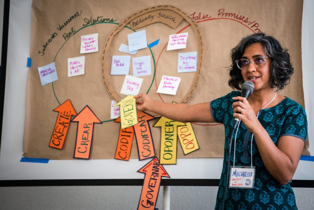 Michelle Mascarenhas stands in front of a board with three overlapping circles drawn on it, for a strategy mapping exercise.