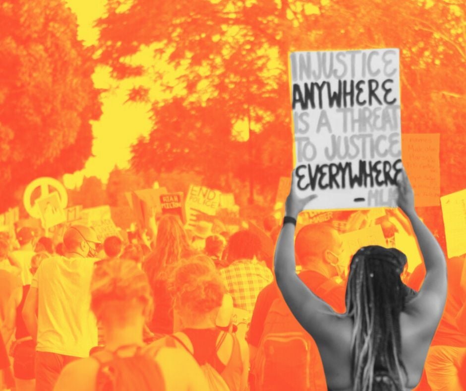 Crowd at a protest in orange duotone. In foreground, in black-and-white, view from the back of a dark-skinned woman with long braids holding a sign that reads, "Injustice anywhere is a threat to justice everwhere."