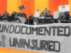 a group of people hold a large banner that reads "Undocumented & Uninsured"