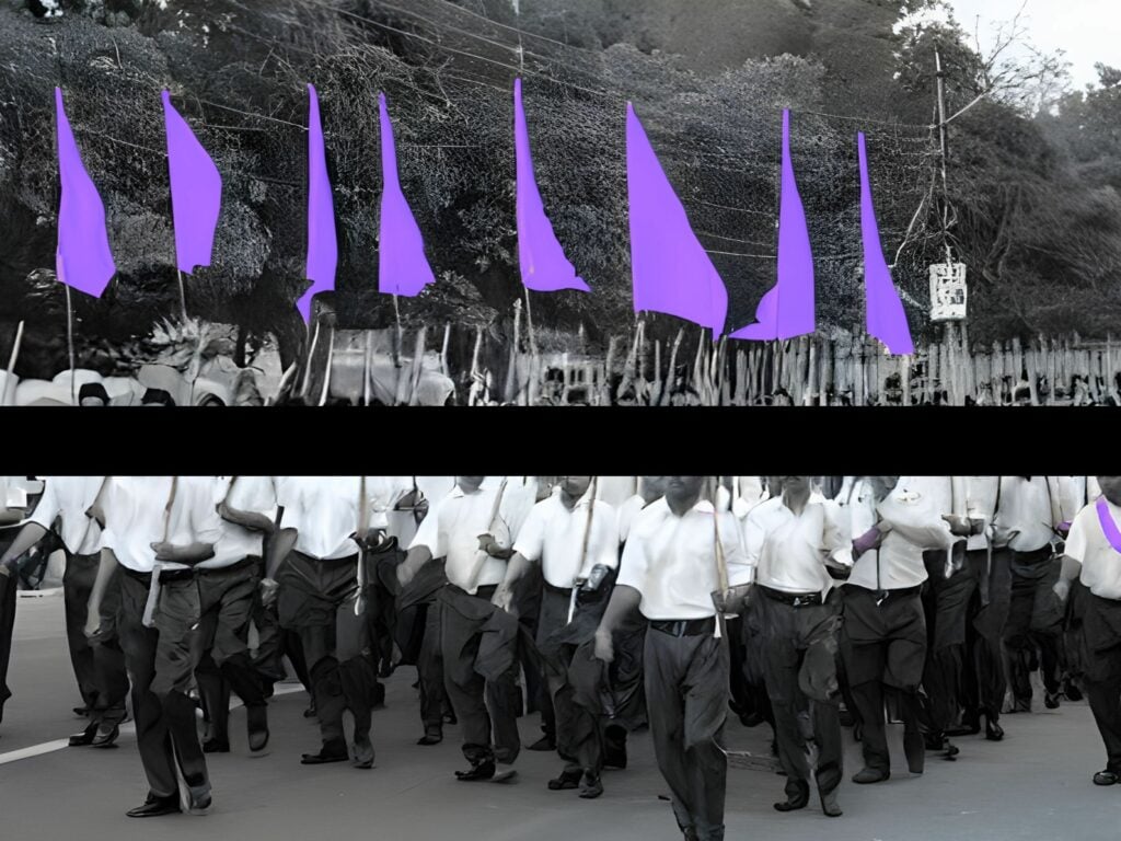 Crowd of men, members of India's RSS, marching with penant flaga.