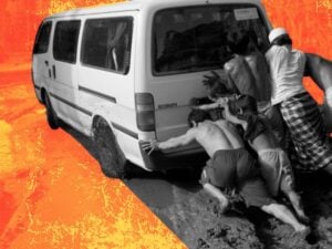 Shot from the back of three men pushing a van out of the mud.