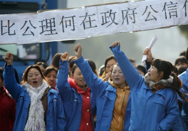 People holding up a banner written in Chinese at a protest