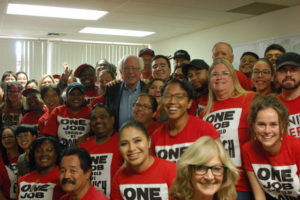 Group of young people wearing red t-shirts with Bernie Sanders in the middle of the group