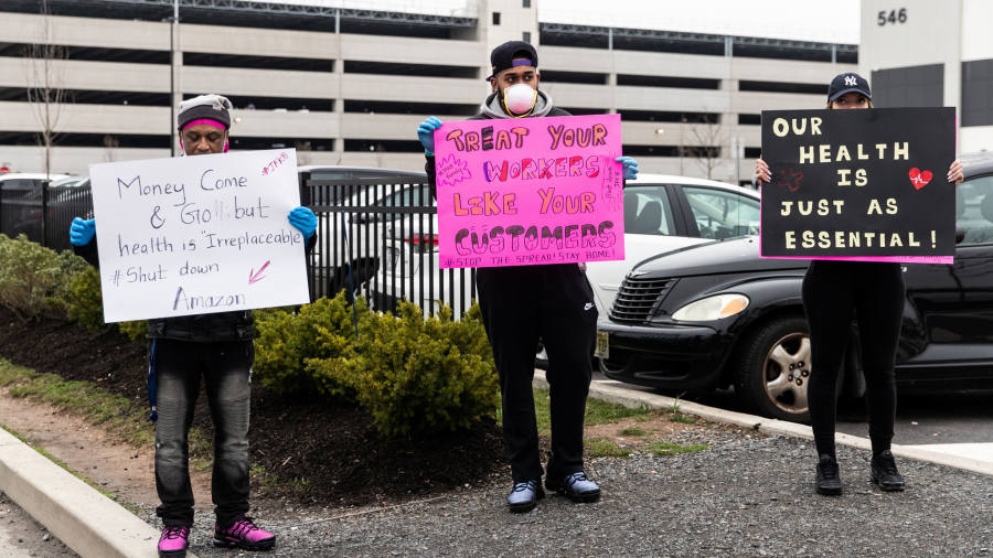 Photograph of 3 people holding signs in a parking lot