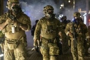 Photo of officers in full camo uniform and wearing gas masks