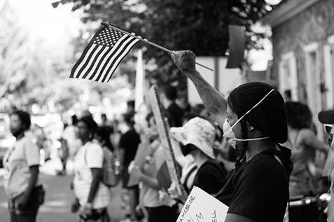 Woman wearing a face mask and waving the American flag