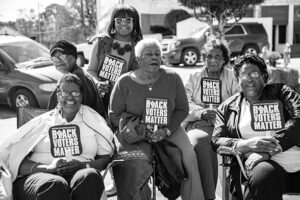 Black women sitting in chairs and standing all wearing Black Lives Matter tshirts