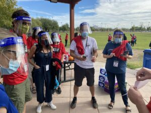 People wearing facemaskes stand in a circle for a short meeting