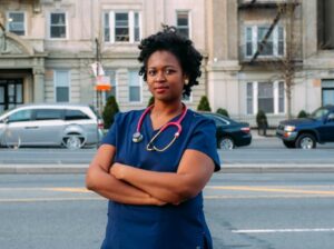 Nurses poses with city street traffic in background