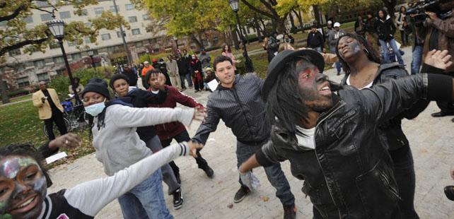 Group of people of many different races standing in a park holding hands in unity