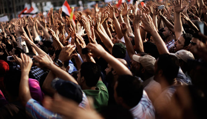 Photo of people at a protest with their hands held in the air