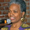 Photo of a gray haired black woman holding a microphone