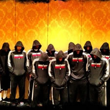 Group of men in hoodies stand with their heads bowed