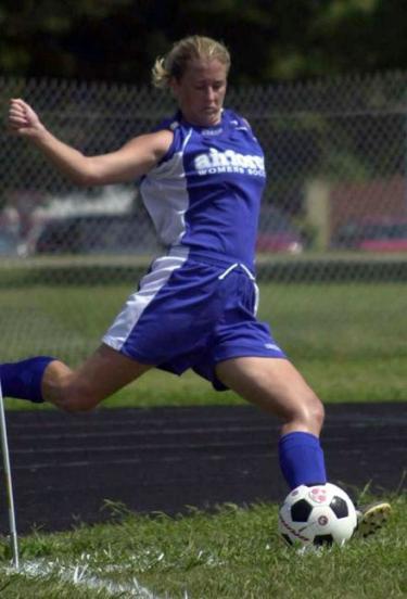 Photo of a person in a blue soccer uniform mid leap on the playing field