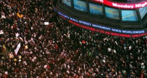 Photo of a sea of people in Times Square. The CNN building is lit up with the slogan 'Occupy Walls Street Movement Goes Worldwide'
