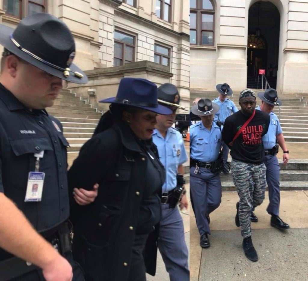 (Left panel) A Black woman in navy-blue hat and suit, wrists tied behind her back, walking between two policemen, one on each elbow. Right panel, a Black man in a black T-shirt and print pants being similarly escorted. Massive old stone steps behind them.