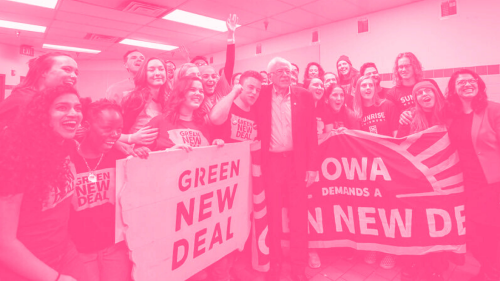 A group of young people gather around Sen. Bernie Sanders with banners calling for the Green New Deal.
