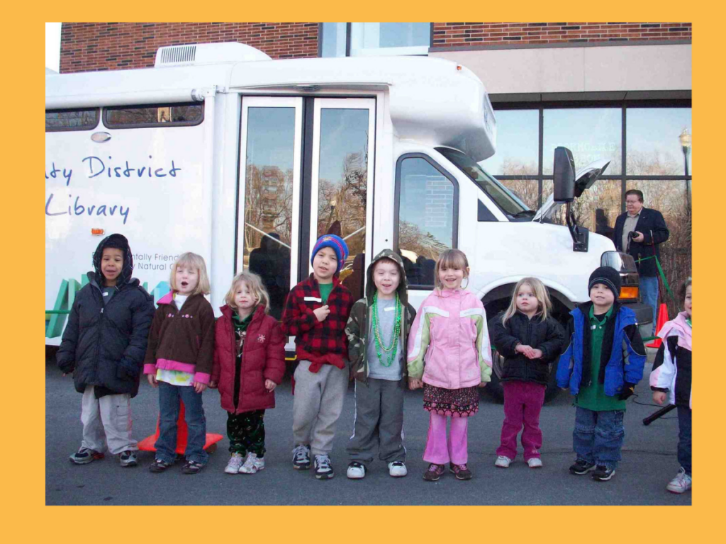 A row of children smiling in front of a van labeled "bookmobile"