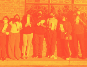 A line of API canvasers, smiling behind masks, standing with sample ballot cards..